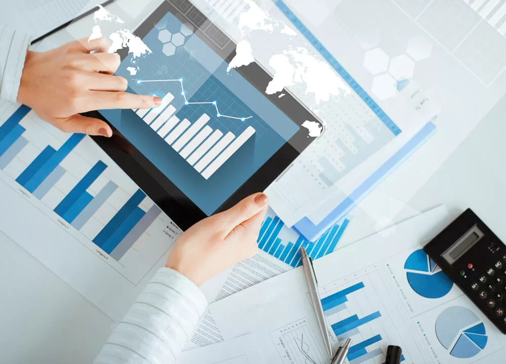 Closeup of woman's hands holding a tablet with financial graphs.